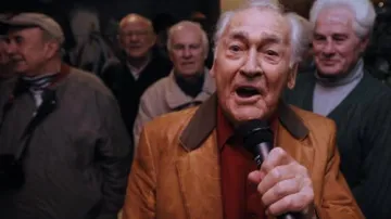 Zpěvák Standa Procházka zpívá slávistickou hymnu obklopen bývalými hráči klubu