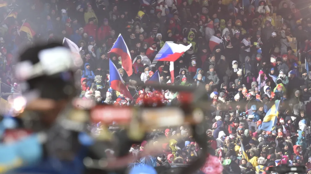 Biatlonista na střelnici a davy fanoušků v zádech