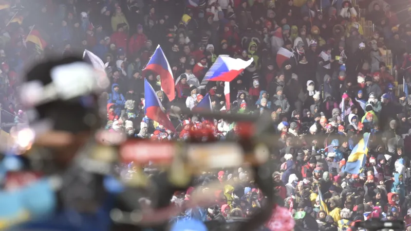 Biatlonista na střelnici a davy fanoušků v zádech