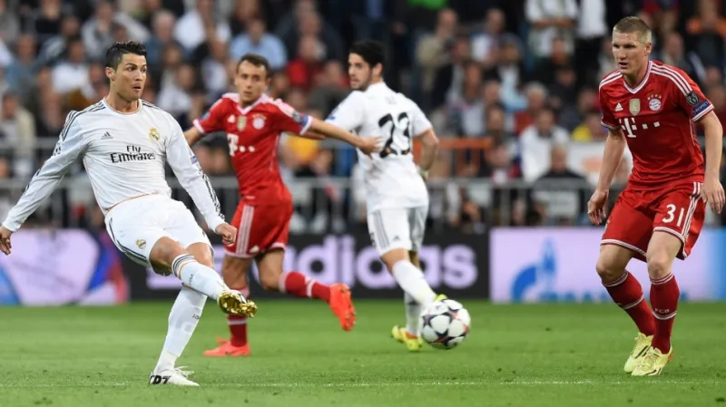 Cristiano Ronaldo odehrává míč před Bastianem Schweinsteigerem