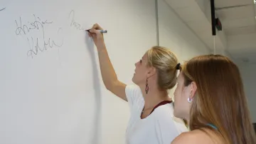 Markéta Sluková se podepisuje v redakci, Kristýna Kolocová přihlíží