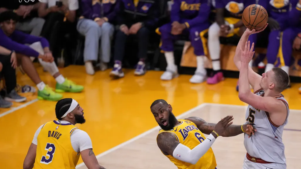 Nikola Jokič z Denveru střílí na koš přes LeBrona Jamese z LA Lakers