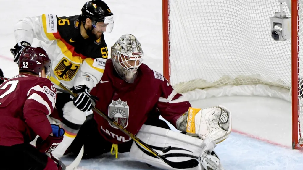 Lotyšský brankář Elvis Merzlikins v souboji s Felixem Schutzem z Německa