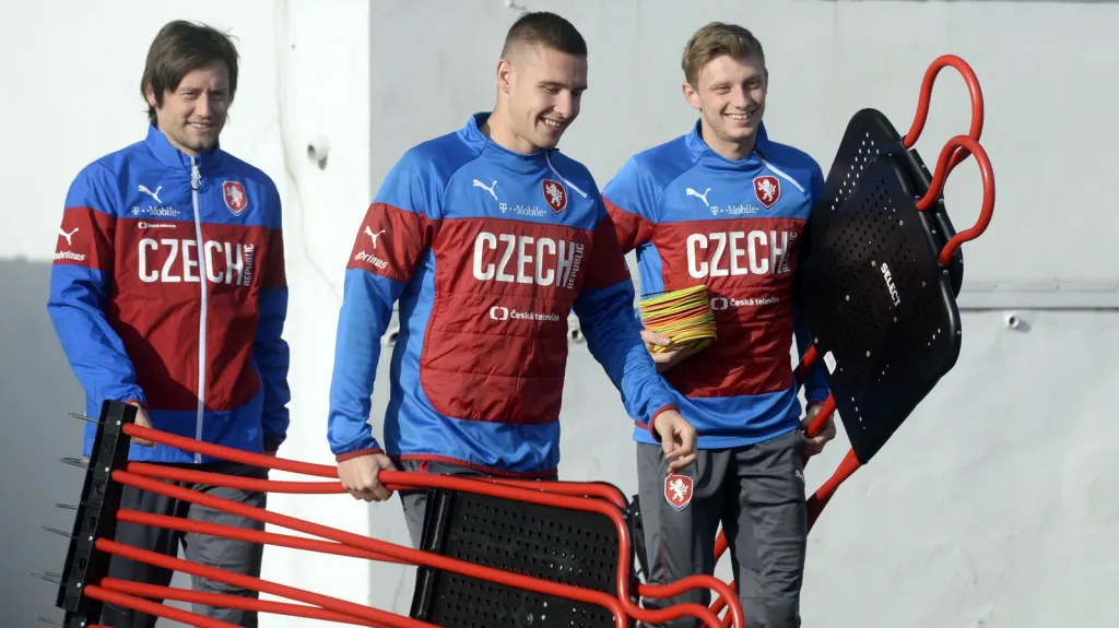 Tomáš Rosický sleduje své mladší spoluhráče, kterak nosí tréninkové pomůcky