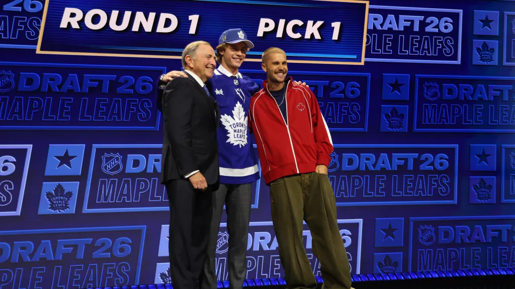 Jednička draftu NHL Gavin McKenna v dresu Toronta pózuje fotografům s komisionářem NHL Garym Bettmanem a zpěvákem Justinem Bieberem