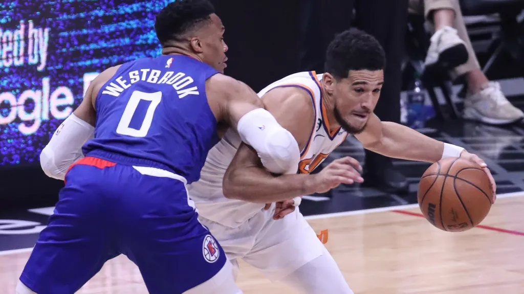 Devin Booker se snaží dostat přes Russella Westbrooka