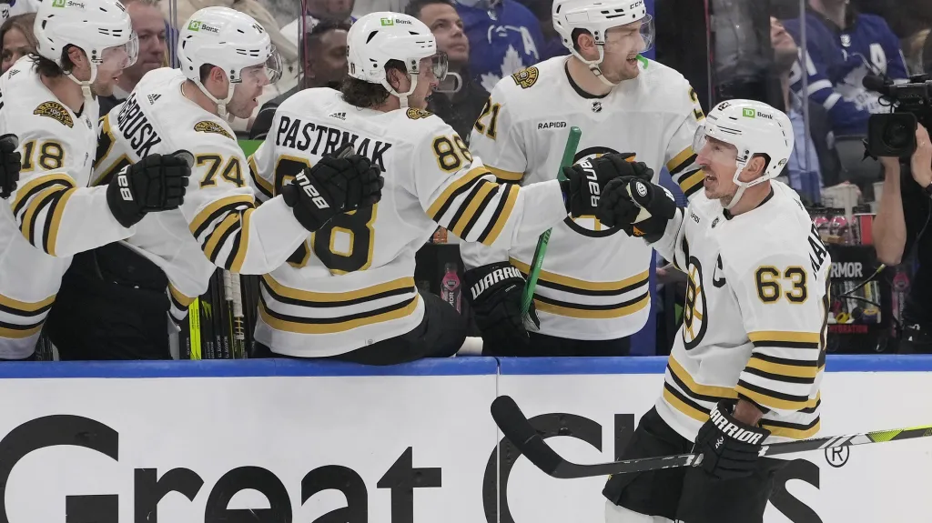 Kapitán Bostonu Brad Marchand slaví s Davidem Pastrňákem a dalšími spoluhráči