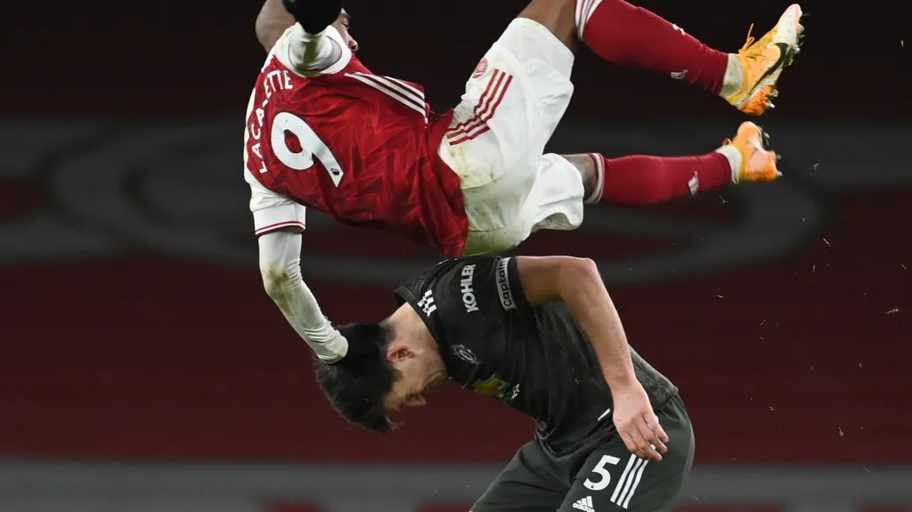 Alexandre Lacazette přepadává přes Harry Maguira