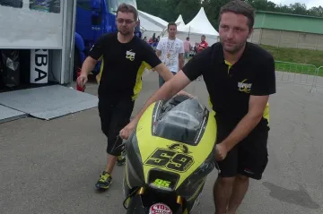 Mechanici tlačí zpět do stanu omlácenou motorku Miroslava Popova