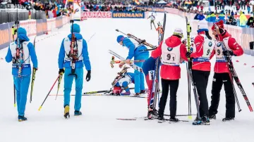 Antona Babikova uklidňují kolegové z ruské reprezentace, zatímco Norové slaví vítězství ve štafetě