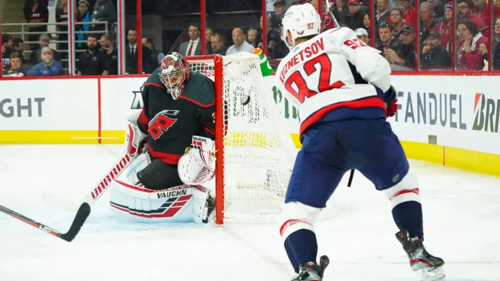 Brankář Caroliny Petr Mrázek kryje pokus Jevgenije Kuzněcova z Washingtonu