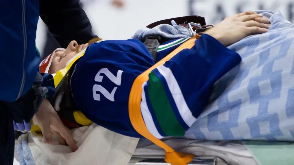 Daniel Sedin na nosítkách po zákroku Paula Byrona