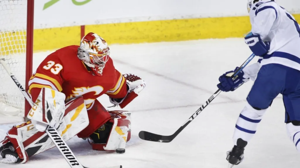 Brankář David Rittich z Calgary čelí nájezdu Mitche Marnera z Toronta