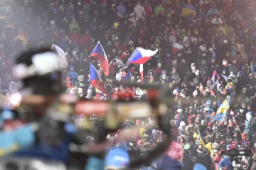 Biatlonista na střelnici a davy fanoušků v zádech