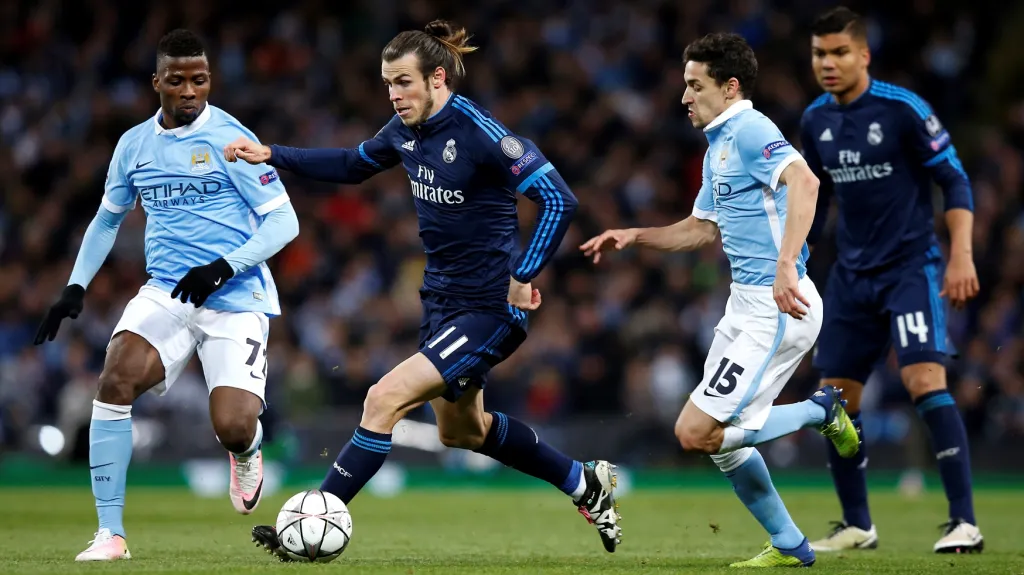 Gareth Bale z Realu Madrid (u míče) se snaží projít mezi hráči Manchesteru City