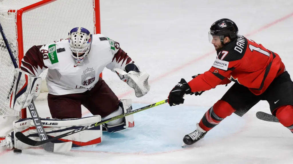 Lotyšský brankář Matiss Kivlenieks zasahuje před Justinem Danforthem