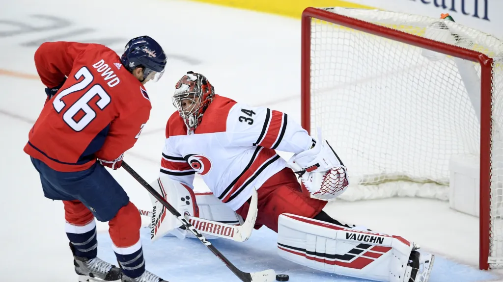 Útočník Capitals Nic Dowd překonává brankáře Caroliny Petra Mrázka