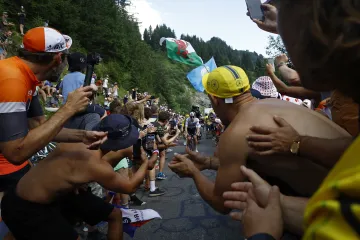 Tadej Pogačar v úzké uličce mezi fanoušky