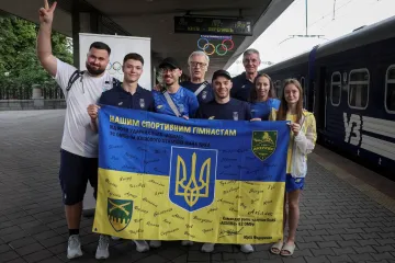 Část ukrajinských olympioniků s podepsanou vlajkou od ukrajinských vojáků