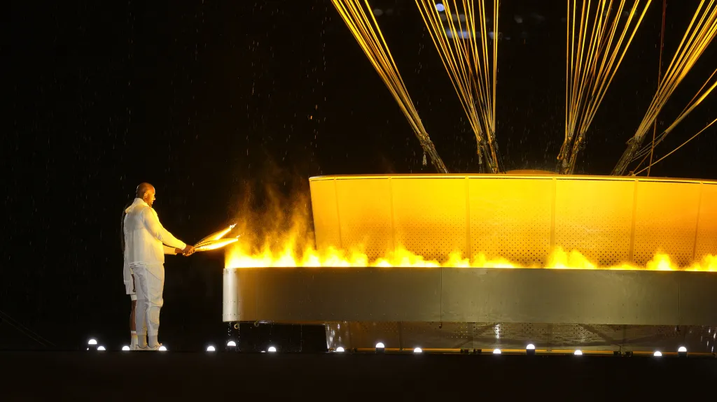 Bývalá atletka Marie-José Pérecová a judista Teddy Riner zapalují olympijský oheň