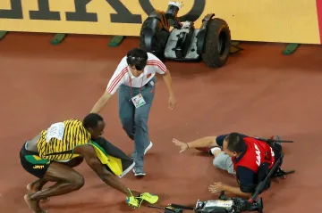 Usain Bolt ve dřepu poté, co ho sestřelil kameraman na segwayi
