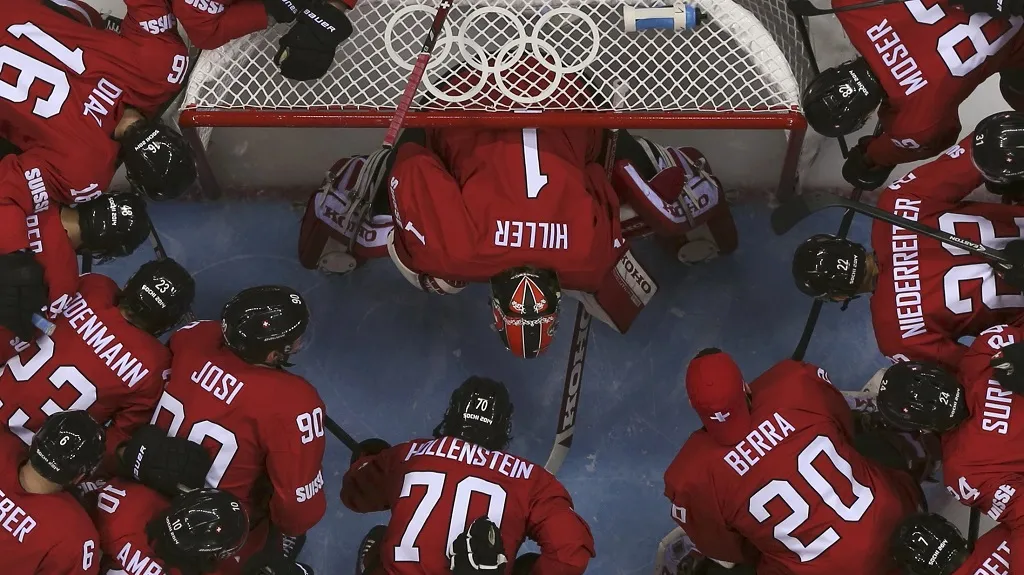 Švýcarský brankář Hiller obklopený spoluhráči před zápasem s Lotyšskem