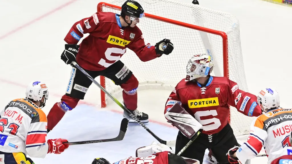 Sparťanský obránce Ondřej Mikliš chytá puk za brankářem Josefem Kořenářem