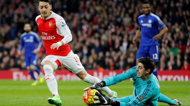 Thibaut Courtois chytá míč před Mesutem Özilem z Arsenalu