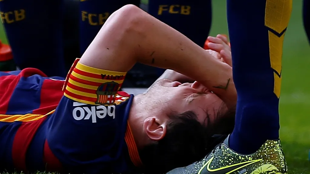 Lionel Messi z Barcelony leží v bolestech na zemi