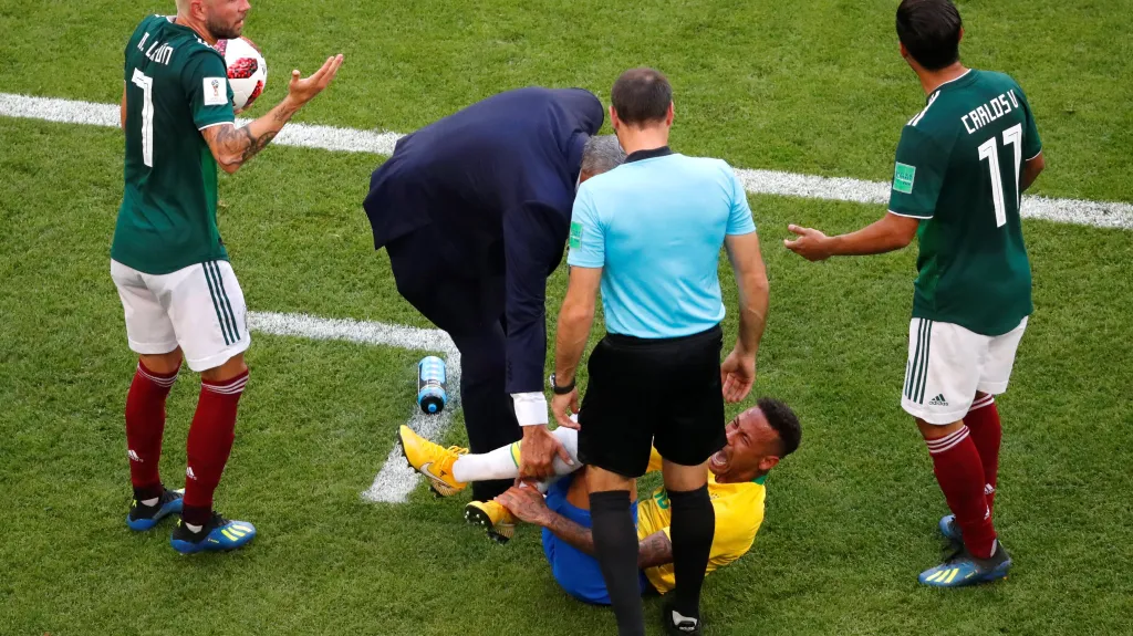 Brazilec Neymar leží na zemi po kontaktu s Mexičany