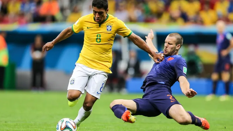 Nizozemec Ron Vlaar přesným skluzem zastavuje Paulinha z Brazílie