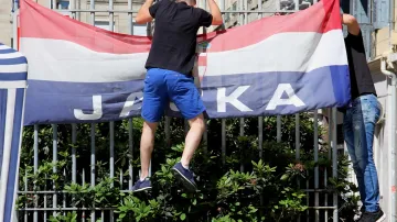 Chorvatský fanoušek připevňuje vlajku na plotě před katedrálou