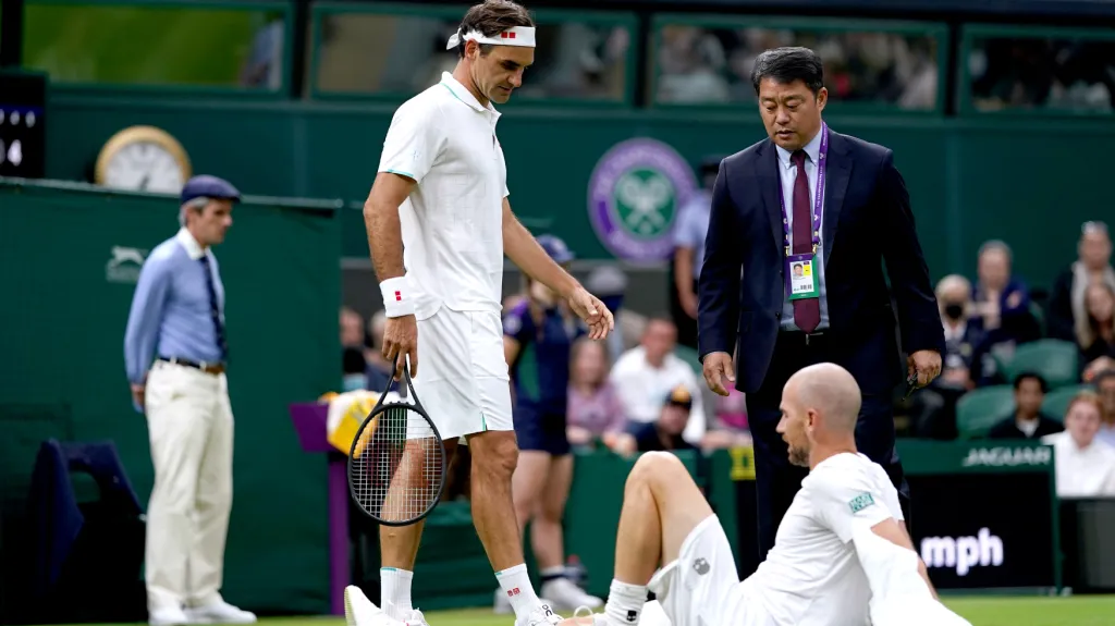 Roger Federer se sklání nad zraněným Adrianem Mannarinem